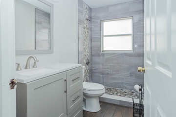 White and gray bathroom with a sink, mirror, and cabinets
