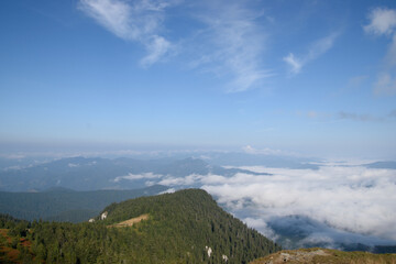 Naklejka premium people on top of a mountain overlooking the clouds and hills