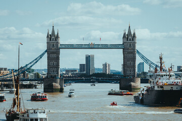 Boat traffic moving along river with bridge in background, London, UK