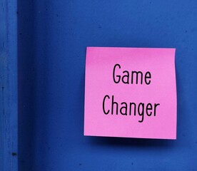 Note stick on blue background with text written GAME CHANGER, an idea, event or element, factor that changes existing situation or activity significant way, player who suddenly changes game outcome