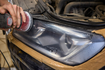 Person using a machine to polish automotive lighting on a car headlight