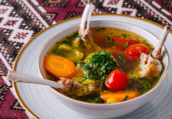 Traditional lamb soup with vegetables on patterned tablecloth