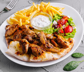 Delicious grilled chicken and sausage with fresh salad and fries
