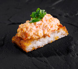 Delectable spicy sushi roll on slate background