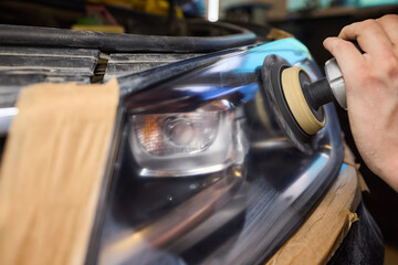 Person using a machine to polish automotive lighting on a car headlight