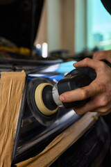 Person using a machine to polish automotive lighting on a car headlight