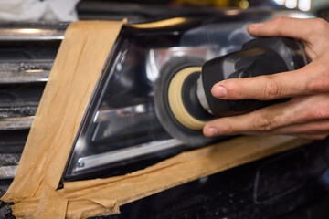 Person using a machine to polish automotive lighting on a car headlight