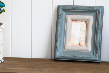 a small vase with flowers on a wood table near a picture frame