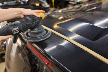 Person using machine to polish black cars automotive exterior