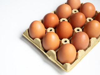 A dozen brown eggs are sitting in a carton on white background