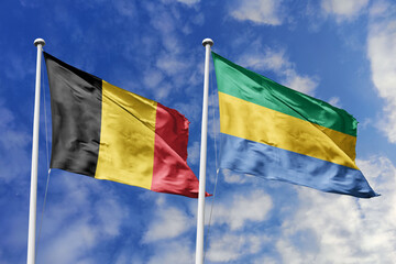 3d illustration. Belgium and Gabon Flag waving in sky. High detailed waving flag. 3D render. Waving in sky. Flags fluttered in the cloudy sky.