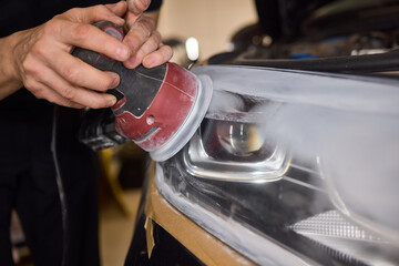 Person using a machine to polish automotive lighting on a car headlight
