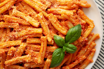 Homemade Italian Casarecce Pasta with Creamy Tomato Sauce, top view. Flat lay, overhead, from above. Close-up.