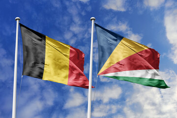 3d illustration. Belgium and Seychelles Flag waving in sky. High detailed waving flag. 3D render. Waving in sky. Flags fluttered in the cloudy sky.