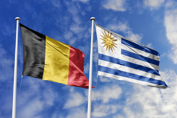 3d illustration. Belgium and Uruguay Flag waving in sky. High detailed waving flag. 3D render. Waving in sky. Flags fluttered in the cloudy sky.