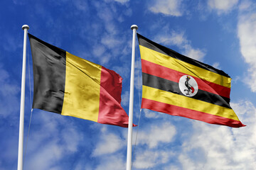 3d illustration. Belgium and Uganda Flag waving in sky. High detailed waving flag. 3D render. Waving in sky. Flags fluttered in the cloudy sky.