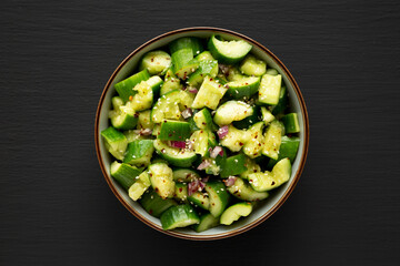 Homemade Smashed Cucumber Salad in a Bowl on a black background, top view. 