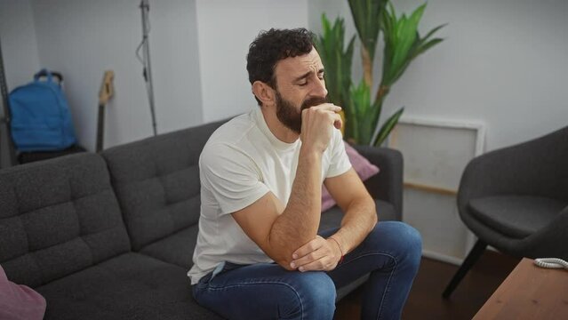 Stressed middle-aged man at home fearfully biting nails, vulnerable expression reflecting life's pressures and anxiety