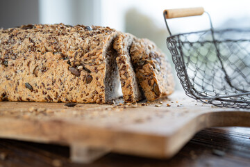 Freshly sliced multigrain bread on wooden cutting board with bread basket. Close-up with short...