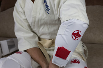 Kyokushinkai karate athlete wears elbow protection, protective equipment for martial arts sparring,...