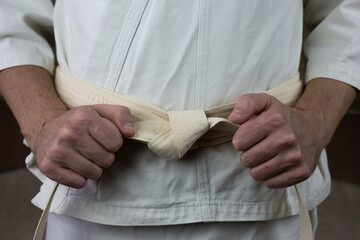 White belt of an athlete in Kyokushin karate, an athlete ties the belt on kimono before the...
