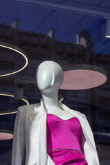 Mannequin in pink dress and white jacket, displaying fashion trends