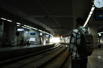 A young man travels alone with a backpack. The guy is standing on the platform and waiting for his...