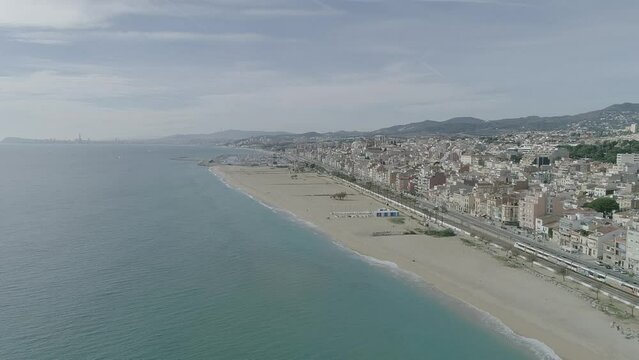 Aerial view of Segur de Calafell, Tarragona, Spain. Drone landscape of a wide sandy beach, long mediterranean coastline with a train passing by.