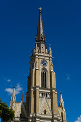 Fototapeta premium Name of Mary Church, also known as Novi Sad catholic cathedral or crkva imena marijinog during a sunny day. The cathedral is one of the most important landmarks. Tower with clock close view.