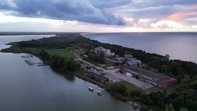 Drone of serene view over Mielno town showcasing buildings on green land surrounded by sea and lake