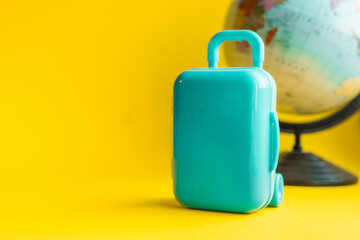 Travel concept. Suitcase and globe on a yellow background with copy space.