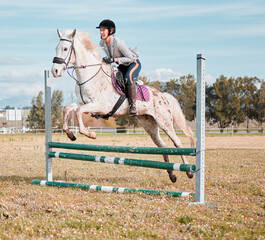 Woman, horse and jump hurdle in outdoor, countryside and equestrian riding practice for...