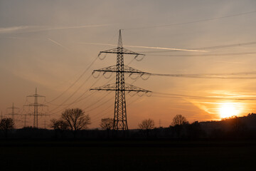 Fototapeta premium Silhouetted power lines in rural area at sunset in Giessen, Germany