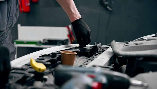 close up At a service station master auto mechanic unscrews bolts on the interior panel of a white car