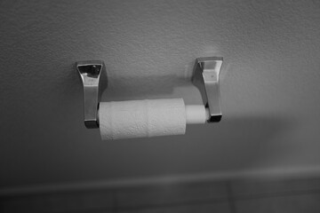 black and white image of a toilet roll on the wall
