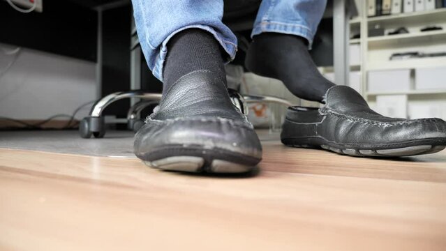 Slow-motion on male feet with black socks wearing black shoes then stepping away