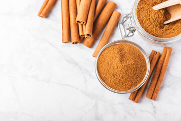 Cinnamon powder in a bowl on a textured wooden background. Spicy spice for baking, desserts and drinks. Fragrant ground cinnamon. Cinnamon stick. Place for text. Copy space.