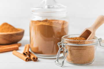 Cinnamon powder in a bowl on a textured wooden background. Spicy spice for baking, desserts and drinks. Fragrant ground cinnamon. Cinnamon stick. Place for text. Copy space.