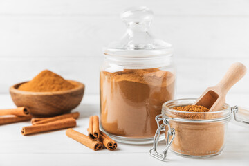 Cinnamon powder in a bowl on a textured wooden background. Spicy spice for baking, desserts and drinks. Fragrant ground cinnamon. Cinnamon stick. Place for text. Copy space.