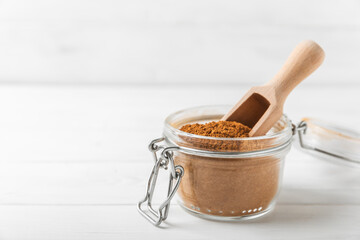 Cinnamon powder in a bowl on a textured wooden background. Spicy spice for baking, desserts and drinks. Fragrant ground cinnamon. Cinnamon stick. Place for text. Copy space.