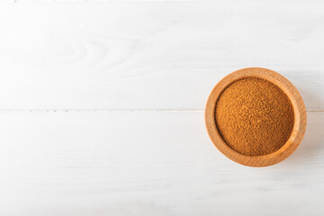 Cinnamon powder in a bowl on a textured wooden background. Spicy spice for baking, desserts and drinks. Fragrant ground cinnamon. Cinnamon stick. Place for text. Copy space.