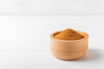 Cinnamon powder in a bowl on a textured wooden background. Spicy spice for baking, desserts and drinks. Fragrant ground cinnamon. Cinnamon stick. Place for text. Copy space.