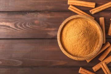 Cinnamon powder in a bowl on a textured wooden background. Spicy spice for baking, desserts and...