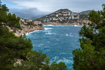 Turquoise sea, rocks, and a small town in Port d'Andratx, Mallorca, Spain.