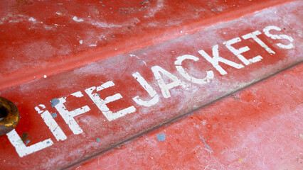 Close up of red, worn grunge container with life jackets sign on passenger ferry vessel