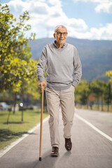 Elderly man with a cane smiling and walking