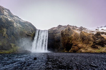 Scenic waterfall cascading with a towering cliff backdrop. Iceland