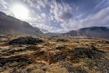 Icelandic landscape featuring brown hills under a blue sky with fluffy clouds