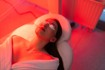 Top view face of female client lying during non-invasive type of phototherapy. Closeup of woman...