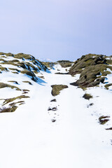 Snow-covered rocks and ground under a clear blue sky